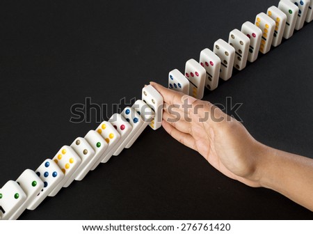 Human hand stopping falling dominos - concept for strategy and problem solving