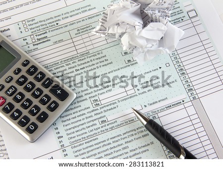 Federal income tax form 1040 with crumpled tax forms, pen and calculator. Concept for  frustration, difficulty and needing help in understanding tax laws and regulations