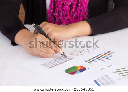 Business executive analyzing sales report with charts and graphs. Person wearing business casual wear in her office room. Concept for woman in business.