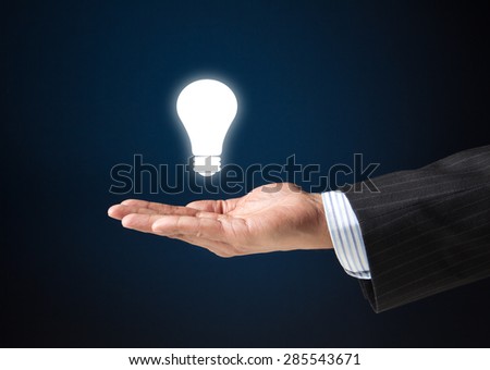 Hand of a businessman with a floating bulb.  Concept image for idea, creativity, genius