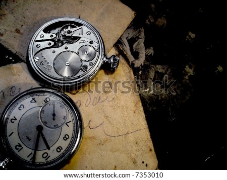 An old fob watch and an old paper with a photo of a group of men\'s faces at the background