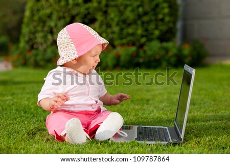 Newborn girl on nature near computer