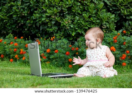 Newborn girl on nature near computer