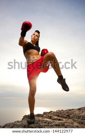 Beautiful kick boxing girl exercising high kick in the nature