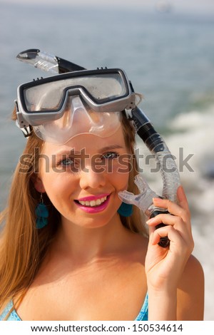 Woman snorkeler with goggles, flippers and snorkel smiling in summer bikini