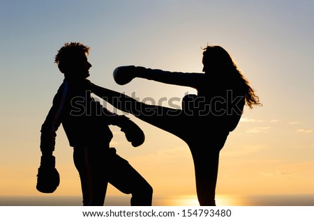 A woman and men is silhouetted in the colorful sky with boxing gloves