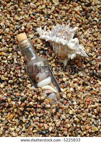 Sea shells and stones in a bottle on sea-beach background