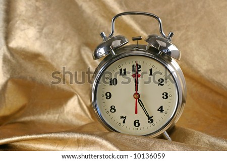 Metallic old-fashioned alarm-clock on gold background