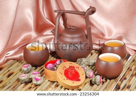 Chinese teapot and cups on a beige satin background