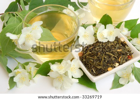 Organic jasmine tea leaves with fresh jasmine flowers and cups of tea on white background