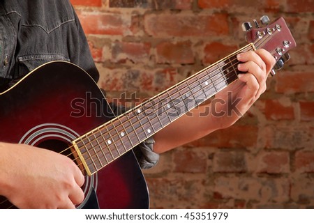 Playing on acoustic guitar on break wall background