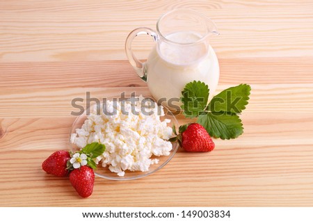 Ripe strawberries, milk and cottage cheese on wood table