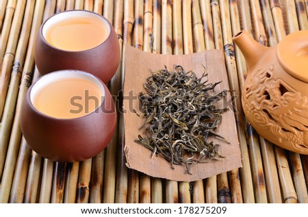 Two cups of aromatic oolong green tea on bamboo mat background