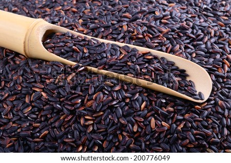 Black wild rice background with bamboo spoon full of grains