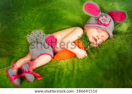 Eight day old smiling newborn baby wearing bunny ears and a bunny tail diaper cover. The baby is sleeping on his stomach.