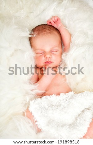 Newborn baby boy asleep on a fur blanket.