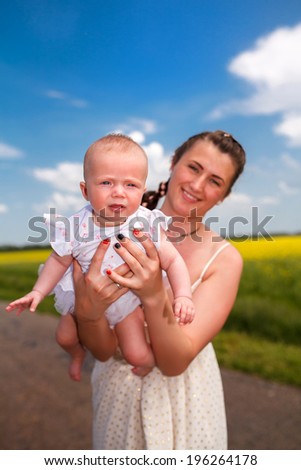 happy family. Mother throws up baby in the sky in nature