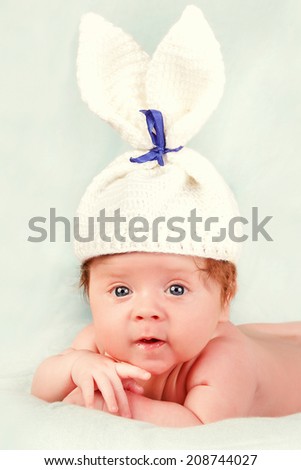Eight day old smiling newborn baby wearing bunny ears and a bunny tail diaper cover.