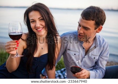 A young couple share a romantic dinner with candles and wine glasses on the sea sand beach
