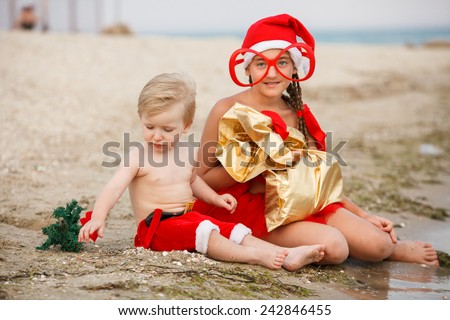 Sweet christmas baby.girl and boy on the beach in Christmas costumes