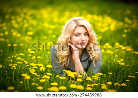 pretty woman lying down on dandelions field, happy cheerful girl resting on dandelions meadow, relaxation outdoor in springtime, vacation