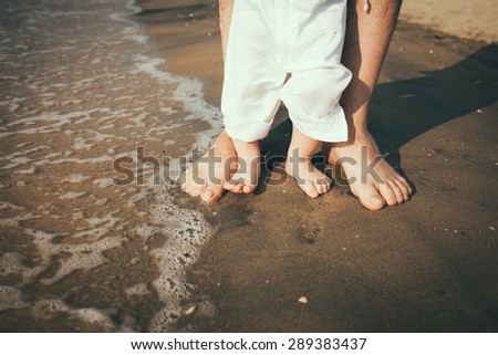 father and baby feet walking on sand beach