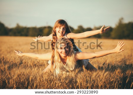 Young happy beautiful mother and her daughter . Happy family. Expressing emotions of joy, freedom, success. Silhouettes on sunny sky