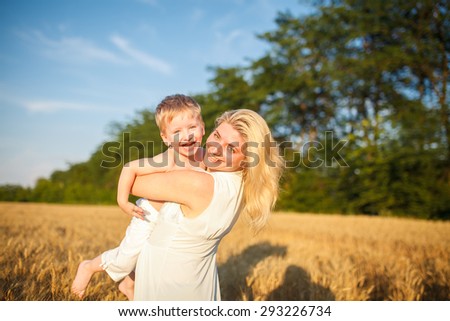 Mom and son having fun by the lake, field  outdoors enjoying nature. Silhouettes on sunny sky.  Warm filter and film effect