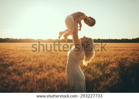 Mom and son having fun by the lake, field  outdoors enjoying nature. Silhouettes on sunny sky.  Warm filter and film effect