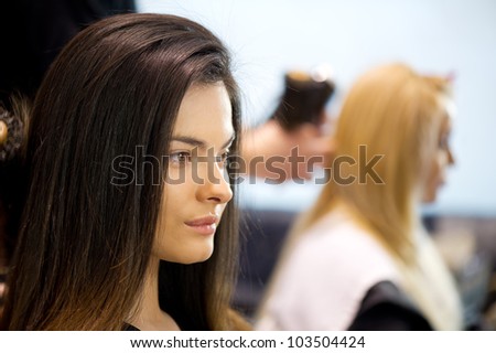 Pretty ladies sitting while hairdresser dries their hair