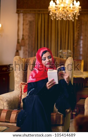 arabian lady with hijab relaxing at her home reading a book