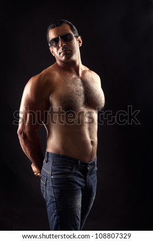 portrait of topless athletic man posing over black background