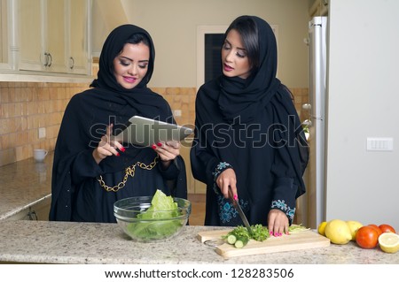 Two Arabian Women gathering cooking & Checking recipe on a Mobile pad