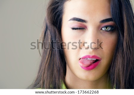 Portrait of happy young woman winking and sticking her tongue out