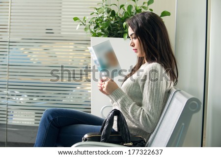 young woman reading brochure in doctor\'s waiting room