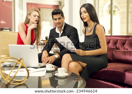 Portrait of a handsome fashionable man with two charming women in a business meeting