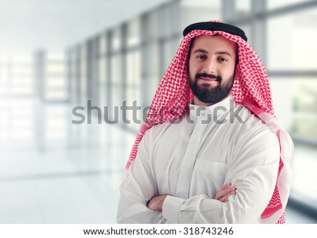 Arab businessman standing in a modern hallway with his arms crossed