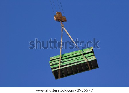 Moving of a cargo by the crane on a background of the bright dark blue sky