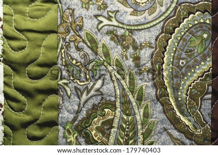 Textile with quilting detail closeup green and brown satin with paisley print
