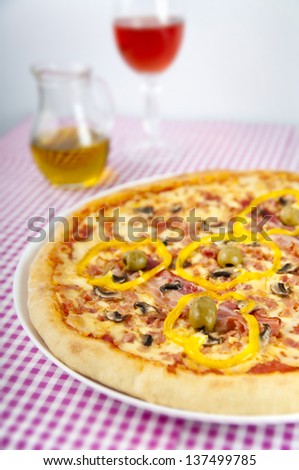Baked pizza with colorful stuffing with glass of wine in the background.