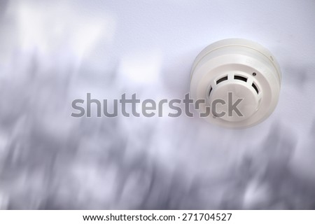 A smoke detector installed at a ceiling with smoke