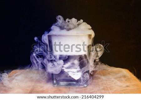 White smoke in glass with dry ice on dark background, Blue & yellow shade dry ice