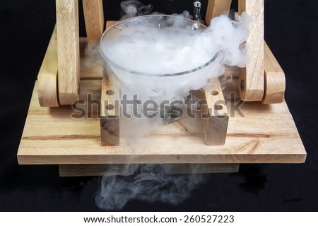 Boiling effect dry ice in glass with wood chair on dark background