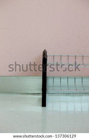 Shoe rack with pink wall, on floor