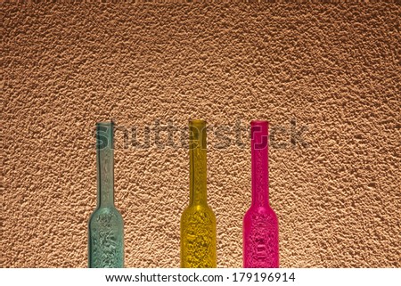 Three blue, yellow and pink  transparent colored bottles