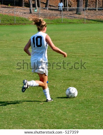 Female soccer player dribbles down field