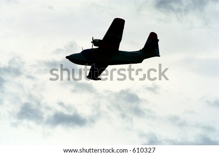 Propeller driven airplane silhouetted against an overcast sky