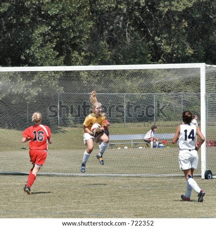 Female soccer goal keeper jumps to save a goal