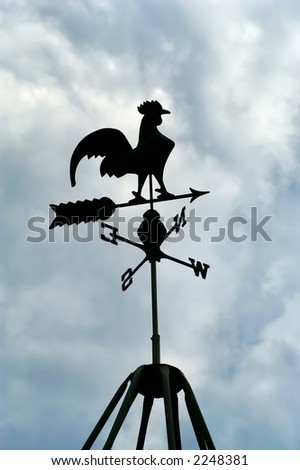 Black rooster weather vane silhouetted against a cloudy sky