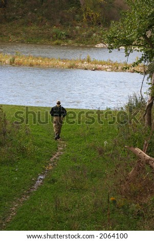 Man walking down a path to go fishing
